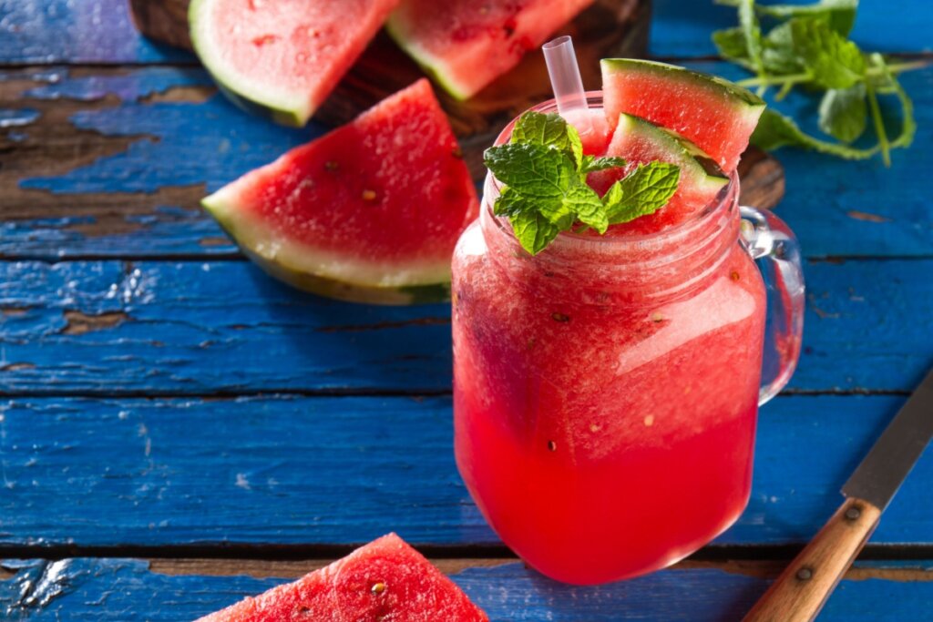 Suco de melancia com hortelã em copo de vidro sobre uma mesa de madeira azul