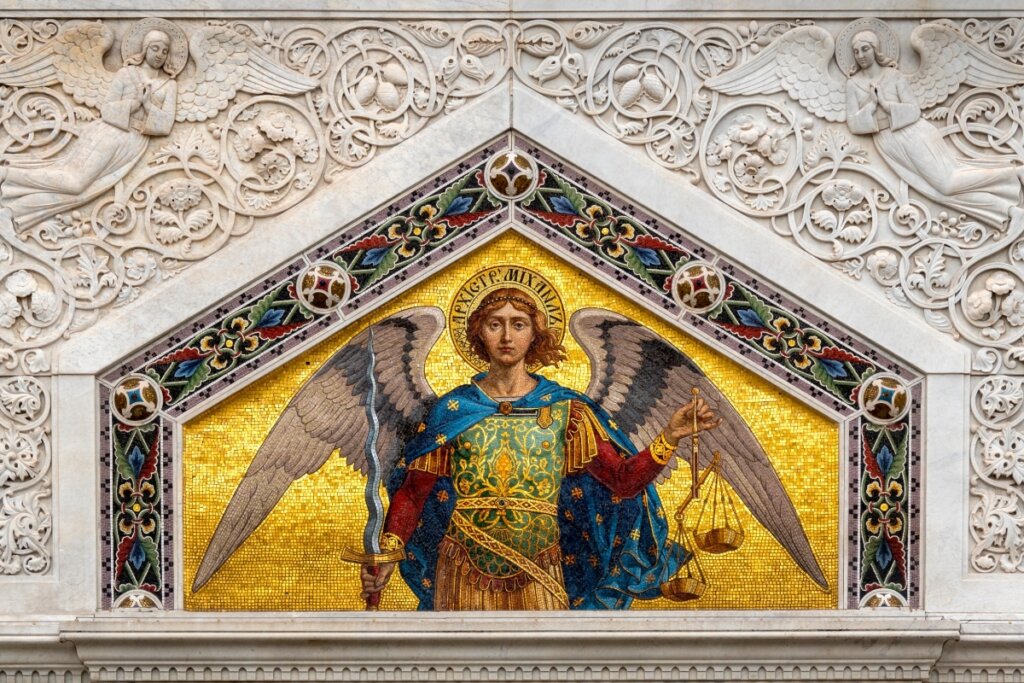 Imagem de São Miguel em parede segurando espada e balança, com manto azul e sobre fundo amarelo