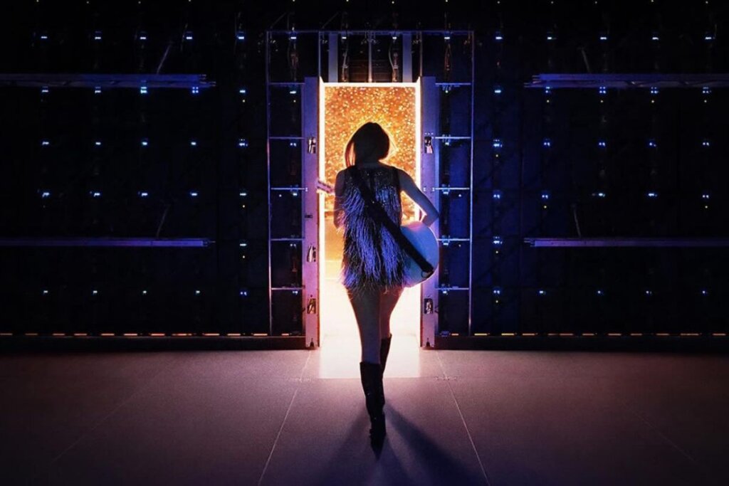 Capa do "Taylor Swift: The End of an Era" com a cantora Taylor Swift segurando um violão e andando em direção a uma porta iluminada 