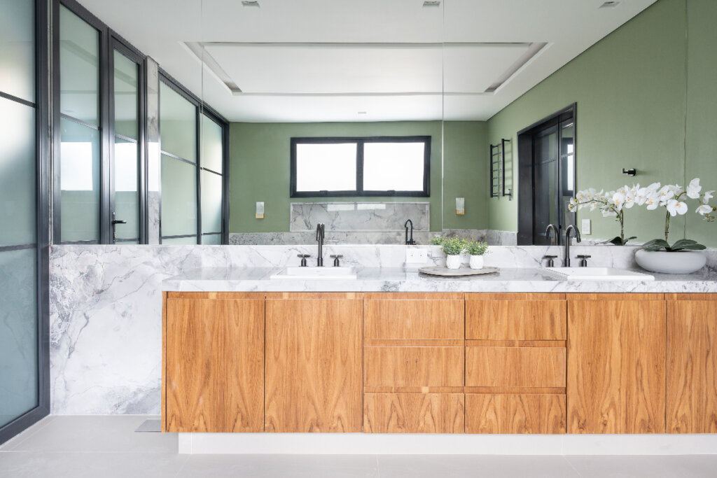 imagem de banheiro com bancada de pia longa com armário de madeira com espelho tomando toda a parede 