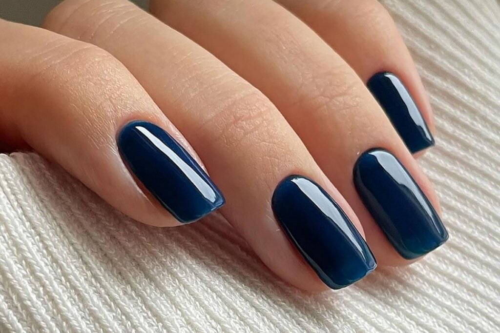 Do clássico ao inesperado: outono abre espaço para cores ousadas nas unhas 23 mão feminina com unhas em tom de azul intenso