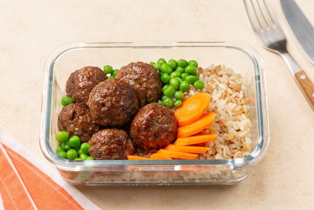 Marmita proteica: 8 receitas fáceis e nutritivas para o dia a dia 5 Almôndegas com arroz integral, ervilha e cenoura em uma marmita de vidro