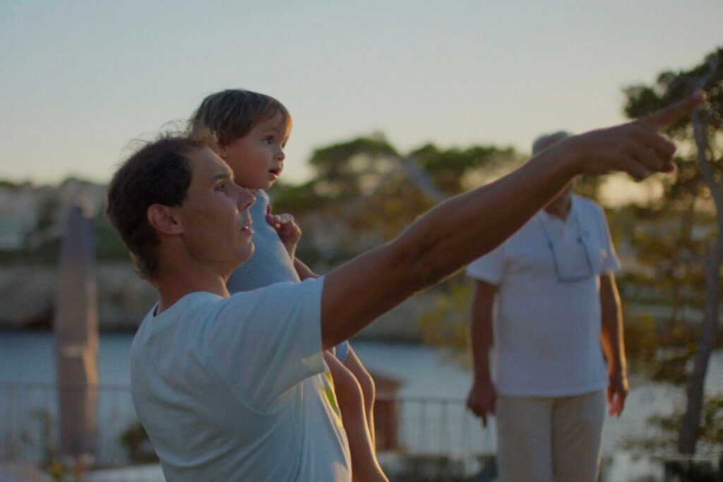 Cena da série documental "RAFA", com o atleta segurando uma criança no colo e apontando para o céu 